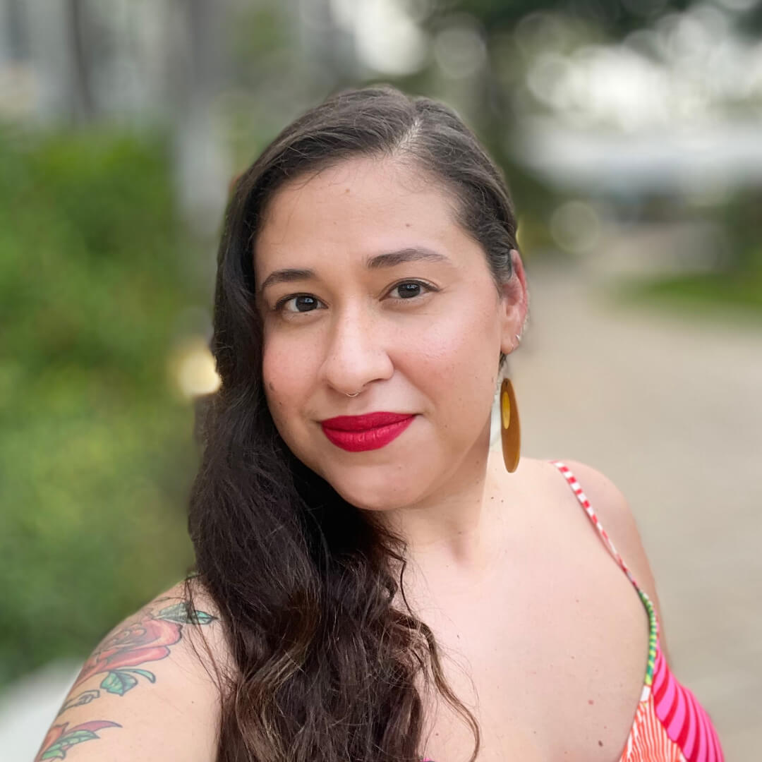 Boricua femme with long brown hair and bright red lipstick.