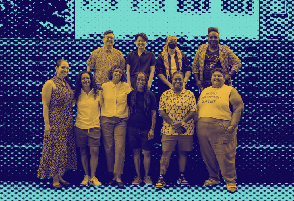 Duotone image of ten NQTTCN members, including the Founding Director Erica Woodland, pose together at a regional gathering. They are outside, standing in front of a striped wooden relief.
