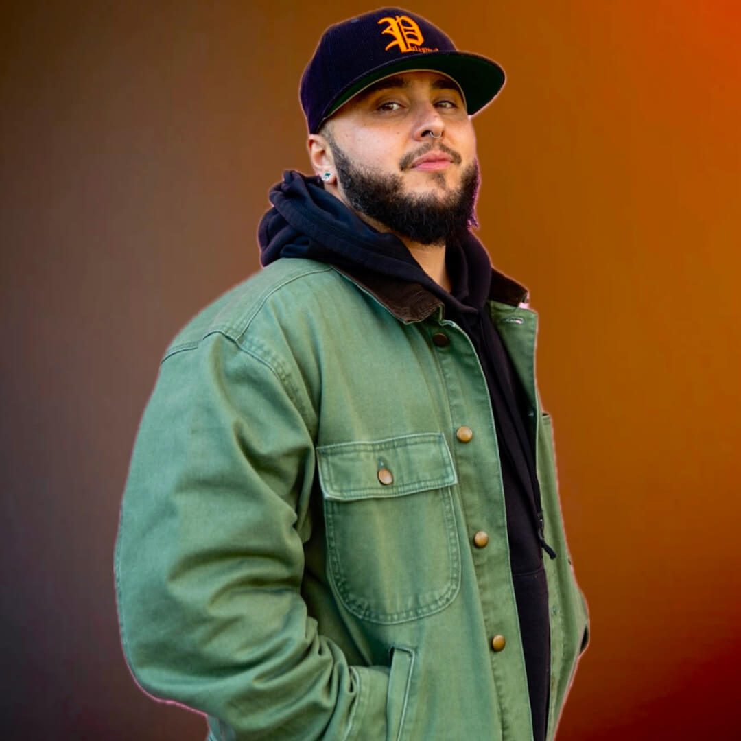 Trans masculine chicano person with Detroit blue hat and jean jacket.